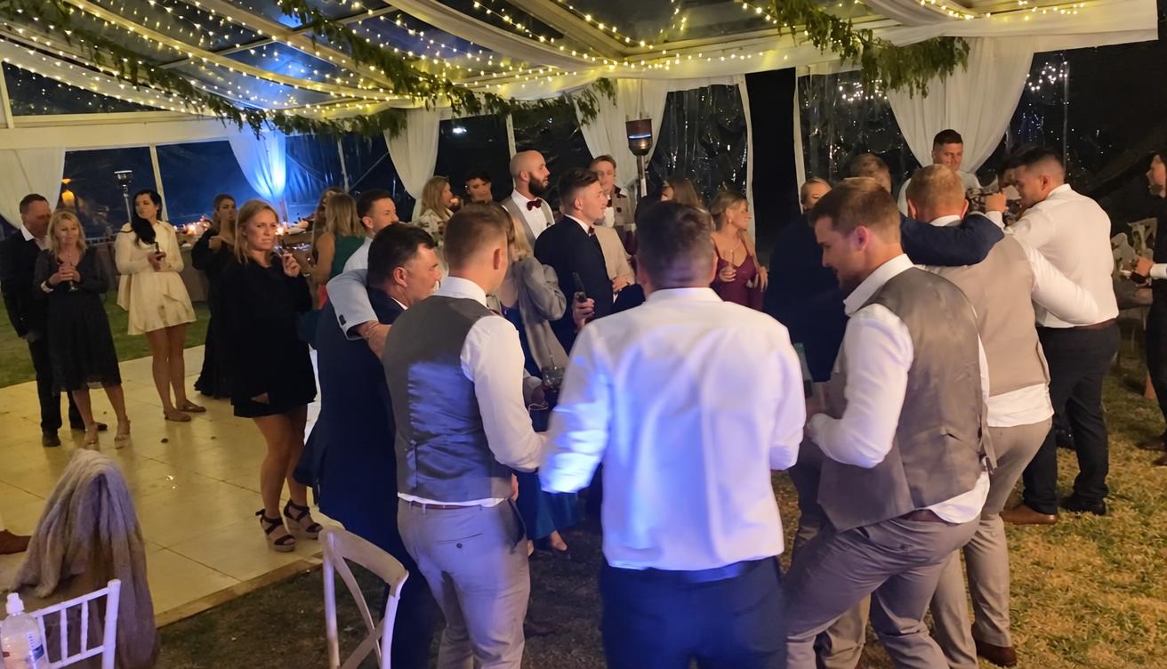 Wedding guests dancing under festoon lights in a marquee